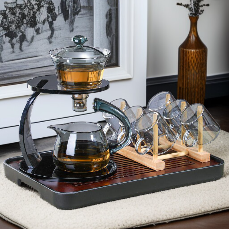 Glass teapot pouring hot tea into matching cups