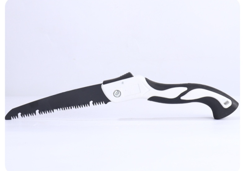 야외에서 접이식 핸드톱으로 나무 자르는 장면